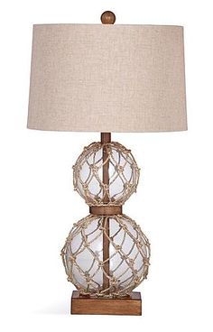 two glass balls on a wooden base with a beige linen shade