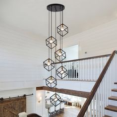 a large chandelier hanging from the ceiling in a living room next to stairs