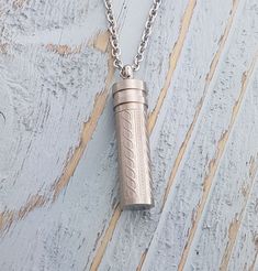 a necklace with a lighter on it sitting on top of a wooden table next to a chain