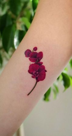 a woman's arm with a red flower tattoo on it