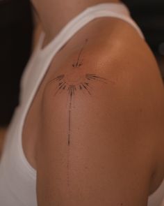 the back of a woman's shoulder with a small sun tattoo on her left arm