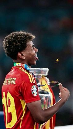 a soccer player holding a trophy in his right hand and blowing it with his other hand