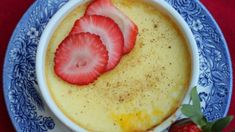 a bowl filled with pudding topped with sliced strawberries on top of a blue and white plate