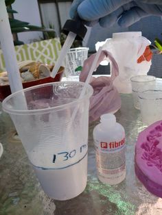 a table topped with plastic cups filled with liquid and other items on top of it