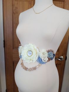 a woman's torso wearing a white and blue flower belt with pearls on it