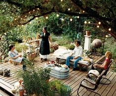 a group of people sitting on top of a wooden deck surrounded by plants and trees