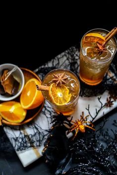 two glasses filled with orange juice and cinnamon sprinkles on top of a table