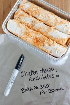 some food is in a metal pan on a table with a pen and napkins