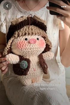 a woman is holding a crocheted snowman with a brown hat and scarf