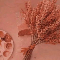 a bunch of flowers sitting on top of a table next to a plate with paint