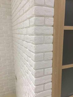 a white brick wall next to a wooden door