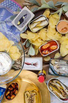 an assortment of food is displayed on a table with chips and dips in bowls