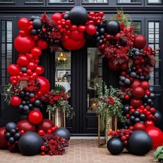 a red and black balloon arch is decorated with balloons, greenery, and flowers