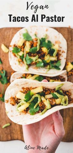 two tacos with avocado and cilantro on top are being held up in front of the camera