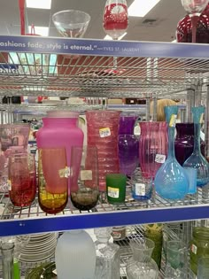 many different colored vases are on display in a glass case at the store for sale