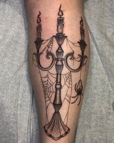 a man's leg with a candle and spider web tattoo on it