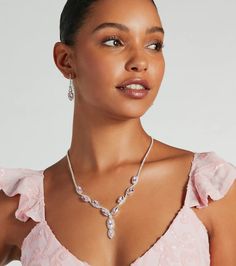 a woman in a pink dress wearing a necklace and earring with an oval shaped diamond