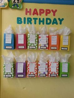 a birthday card display with colorful boxes and tags on the front, hanging from a yellow wall