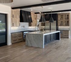 a large kitchen with an island in the middle and wooden flooring on both sides