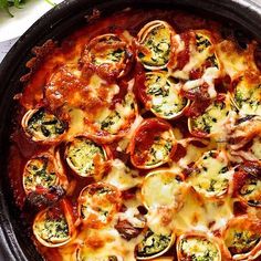 a close up of a pizza in a pan with cheese and spinach on top