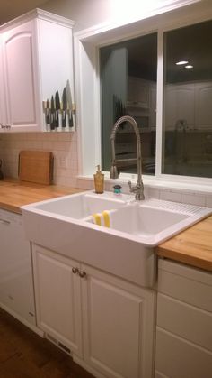 a kitchen with white cabinets and wooden counter tops, along with a large window over the sink