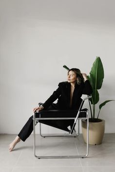 a woman sitting in a chair next to a potted plant with her eyes closed