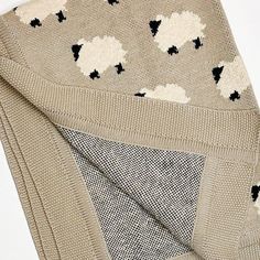 a knitted sweater with sheeps on it is folded up to show the pattern