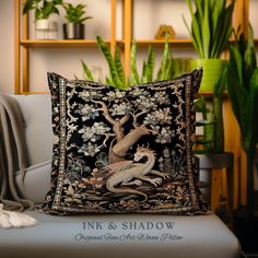 a decorative pillow sitting on top of a white couch next to a potted plant