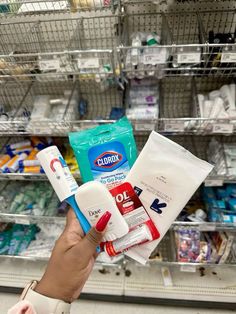 a person holding up some toilet paper and toothpaste in front of a store shelf