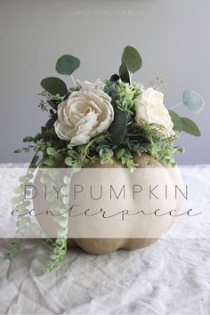 a white pumpkin filled with flowers and greenery on top of a table next to the words diy pumpkin centerpiece