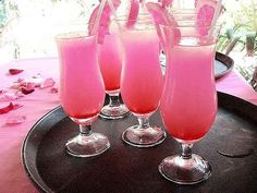 three glasses filled with pink liquid on top of a black tray