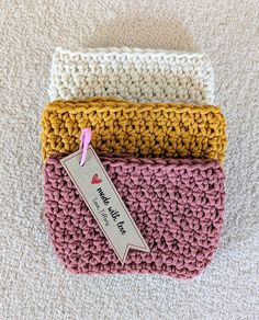 three crocheted purses sitting on top of a white carpet next to each other