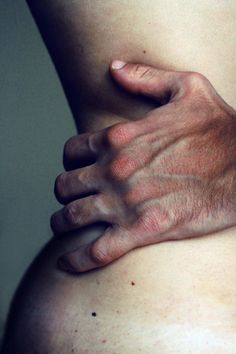 a black and white photo of a person's hand on the stomach