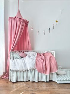 a pink canopy bed in a white bedroom with striped bedspread and pillow cases