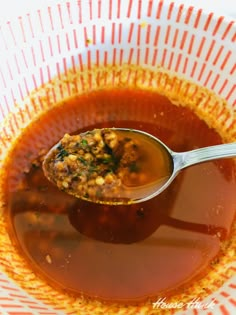 a spoon full of soup in a bowl with orange and white stripes on the side