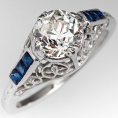 an antique style diamond and blue sapphire engagement ring with filigrees on the sides