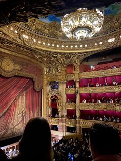 an auditorium filled with people and red curtains