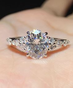 a woman's hand holding an engagement ring with a large diamond in the center