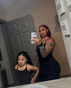 a woman takes a selfie with her daughter in the bathroom mirror while they both look at their cell phones