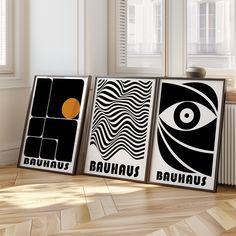 three black and white posters with an orange eye on them in front of a window