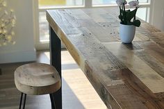 a wooden table with two chairs and a potted plant sitting on top of it