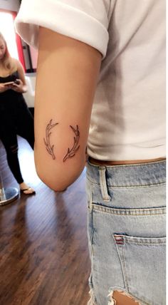 a woman with a tattoo on her arm is standing in front of a mirror and looking at the camera