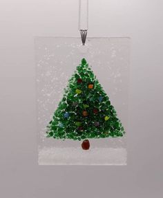 a glass ornament with a green christmas tree on it