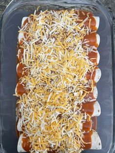 an enchilada with cheese and sauce in a glass dish on a table