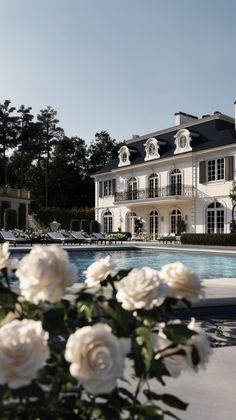 a large white house with a pool and roses in the foreground