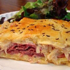 a sandwich on a paper plate next to a salad