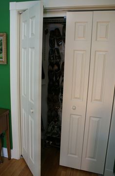 an open closet door with shoes on the floor in front of it and a green wall