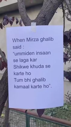 a sign posted on a tree in front of a building that says, when mizza ghabb said ummiden insan se laga kar