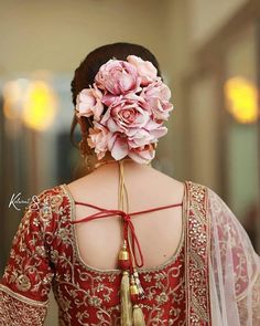 the back of a woman's head with flowers in her hair, wearing a red and gold lehenga