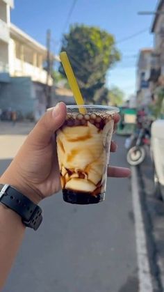 a person holding up a cup with ice cream and chocolate in it on the street